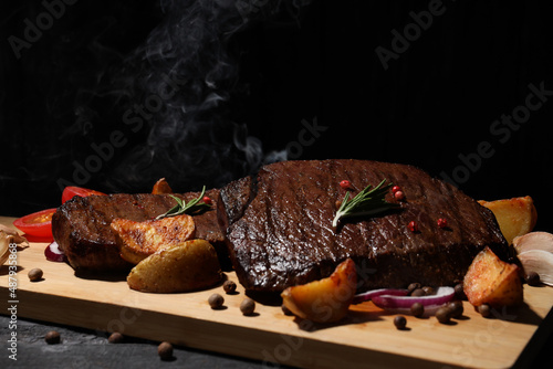 Concept of tasty food with beef steaks on dark background