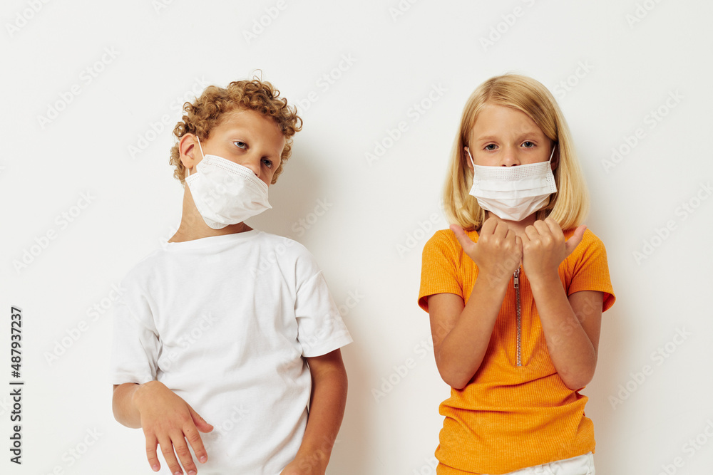 Small children fun medical mask stand side by side close-up lifestyle unaltered
