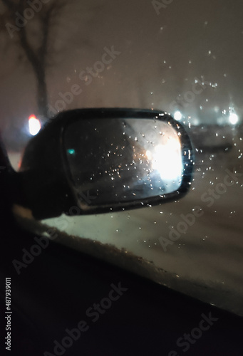 car mirror through glass with drops in the dark