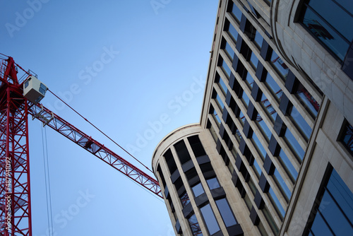 Building facade with semi-circular segments and reflective glass windows. Red construction site crane. Oblique view from below. Modern architecture in Stuttgart, Germany.