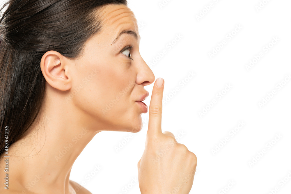 Excited young  woman with a finger on her lips