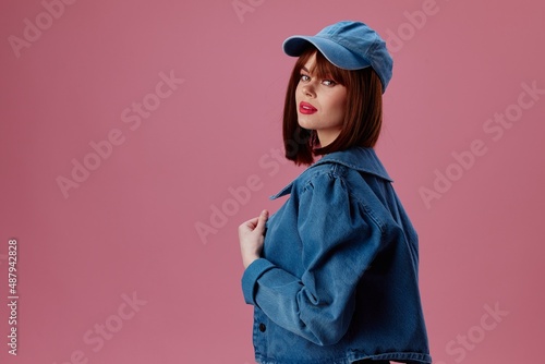 Positive young woman in a cap and denim jacket posing studio model unaltered