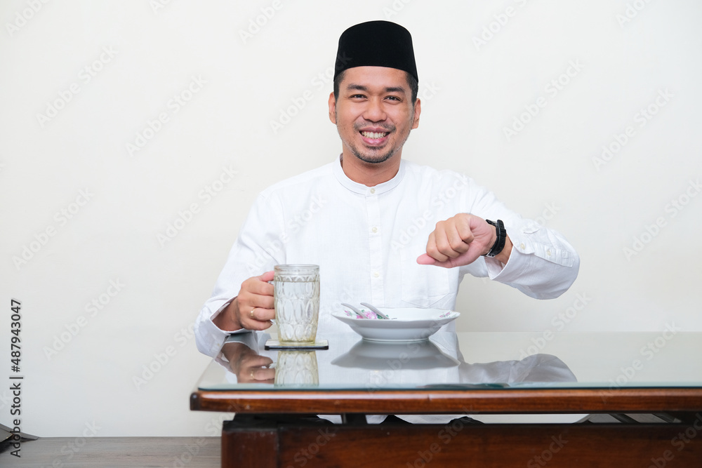 Moslem Asian man smiling while sitting in the dining table before break fasting Moslem Asian man smiling while sitting in the dining table before break fasting