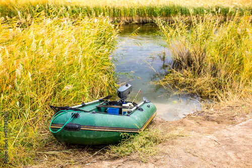 Inflatable boat on the river bank in the reeds. Fishing, male hobby.