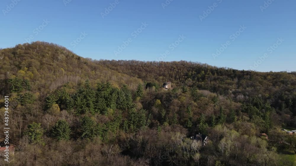 Overview of catholic shrine with monastery built into the side of the mountain. Sun shining off the tree covered mountain in autumn with clear blue sky. Overview of catholic shrine with monastery built into the side of the mountain. Sun shining off the tree covered mountain in autumn with clear blue sky.