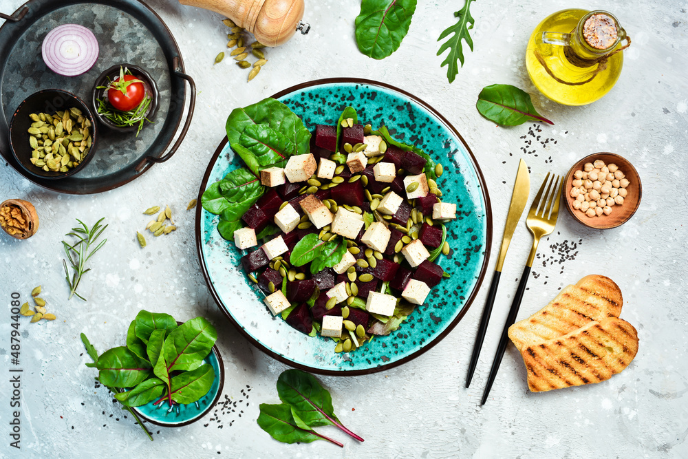 Beet salad, tofu cheese, spinach and pumpkin seeds. The concept of healthy eating. On a stone background. Top view. Beet salad, tofu cheese, spinach and pumpkin seeds. The concept of healthy eating. On a stone background. Top view.