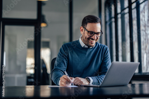 Happy caucasian man in a blue sweater, checking the budget of his company.