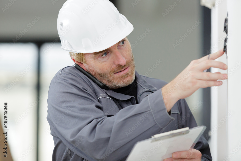 technician pressing switch smartphone balanced between ear and shoulder technician pressing switch smartphone balanced between ear and shoulder