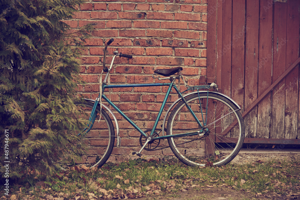 Old rusty vintage bicycle leaning against a brick wall.