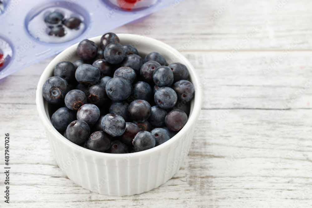 A bowl of blueberries in wooden table. A bowl of blueberries in wooden table.