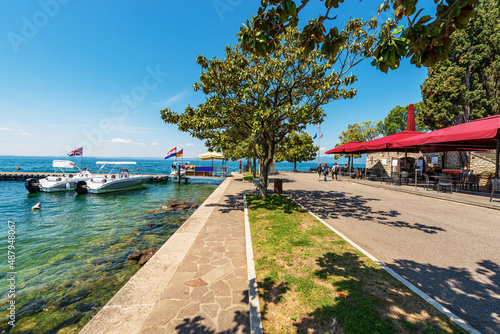 Billede på lærred Promenade on lakeshore of Lake Garda (Lago di Garda) with a small wooden pier and two motorboats