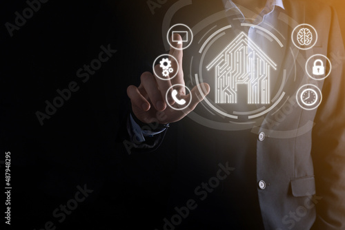 Businessman hold house icon.Smart home controlled, intelligent house, and home automation app concept.Pcb design and person with smart phone. Innovation technology internet Network Concept.