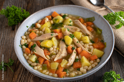 Plate with chicken soup, cooked with vegetable, potatoes and white beans