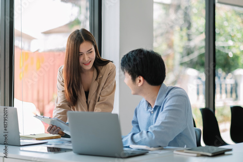 Two young asian business people analyze the results and discuss them.