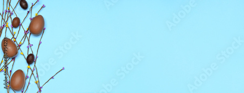 Photography Tasty chocolate Easter eggs and spring branches on blue background with space fo