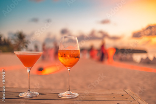 Sticker Two cocktail drinks with blur beach party people and colorful sunset sky in the background