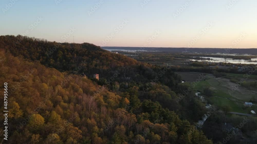 Aerial view around the mountain to oversee the Mississippi River and sunset in distance, back around to see the church building tucked into the trees on side of the mountain. Aerial view around the mountain to oversee the Mississippi River and sunset in distance, back around to see the church building tucked into the trees on side of the mountain.