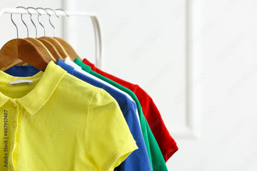 Obraz premium Rack with clean t-shirts near light wall