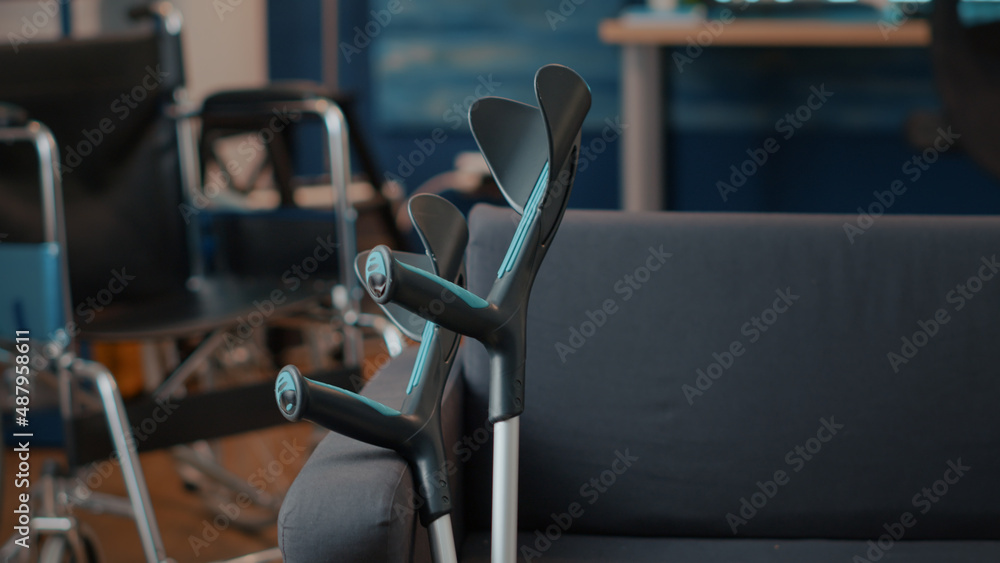 Fototapeta premium Crutches on empty couch in living room to give mobility support to people with chronic disability or injury. Walking sticks helping with transportation and physical accessibility. Walk crutch