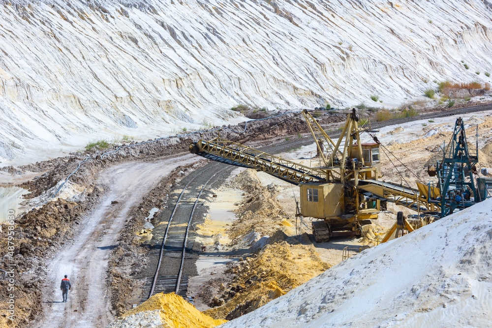 Quarry extraction porcelain clay(kaolin) and quartz sand in the open pit mine. Powerful industrial belt conveyor loader near the access railway track at the deposit opening site. Quarry extraction porcelain clay(kaolin) and quartz sand in the open pit mine. Powerful industrial belt conveyor loader near the access railway track at the deposit opening site.