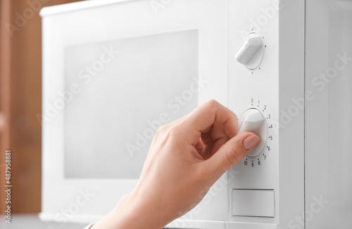 Young woman using modern microwave oven, closeup
