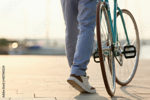 Fotografia Young man with bicycle on embankment, closeup