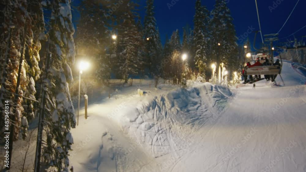 Skilift at night with riders moving down the slope Skilift at night with riders moving down the slope