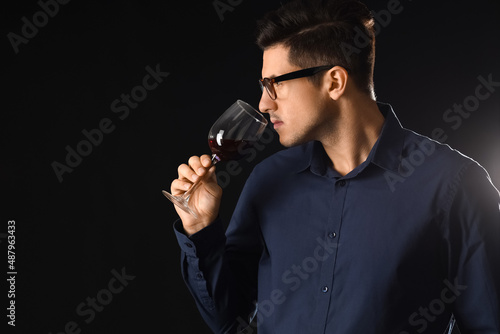 Young male sommelier tastin...