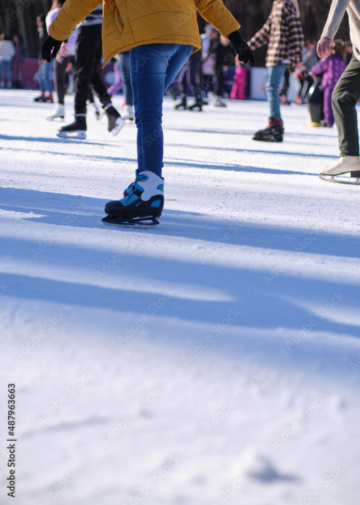 Fototapeta premium Unrecognizable people skating on ice skating rink