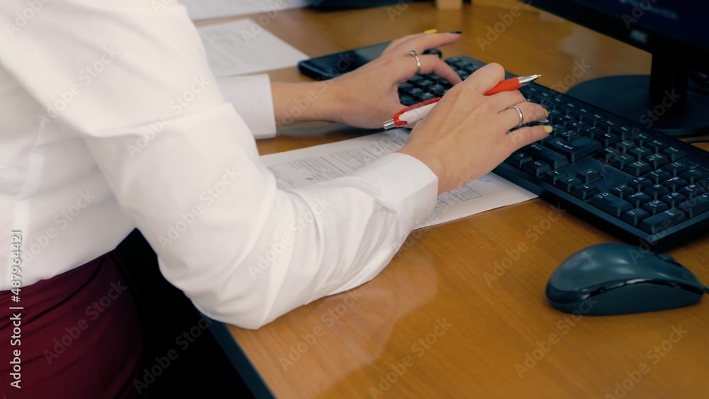 Office worker during work. Woman fills out a statement on the keyboard. - obrazy, fototapety, plakaty 