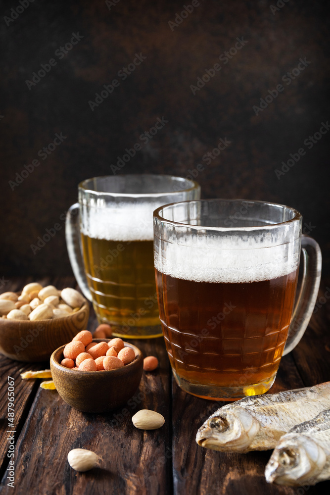 Alcohol drinkpint of lager and pint of stout, craft beer. Two Glass of Beer with foam and snacks on a wooden rustic background. Traditional German wheat beer. Copy space. Alcohol drinkpint of lager and pint of stout, craft beer. Two Glass of Beer with foam and snacks on a wooden rustic background. Traditional German wheat beer. Copy space.