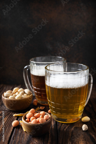 Alcohol drink pint of lager and pint of stout, craft beer. Two Glass of Beer with foam and snacks on a wooden rustic background. Traditional German wheat beer. Copy space.