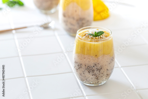 Delicious mango and chia pudding in a glass on the white ceramic tile table close up. Healthy morning breakfast concept photo