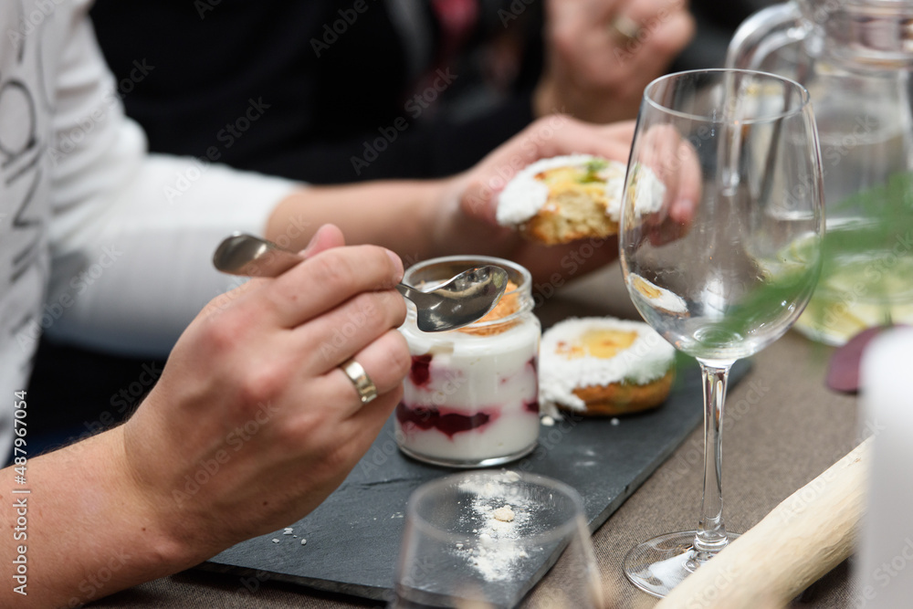 Woman eats dessert in a glass cup, with Jello, yogurt and topping served in a restaurant. Mini desserts