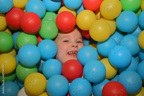 A cheerful girl is playing in the playroom in the pool with balls of different colors