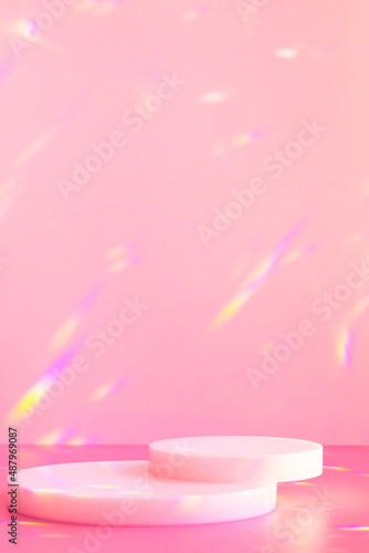 Abstract minimal scene - empty stage, cylinder podiums on soft pink background with rainbow crystal light refraction sparkles. Pedestal for cosmetic product and packaging mockups display presentation