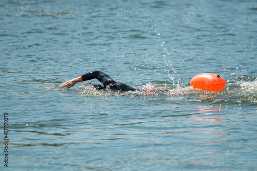 Swimmer in wetsuit with buoy in river water