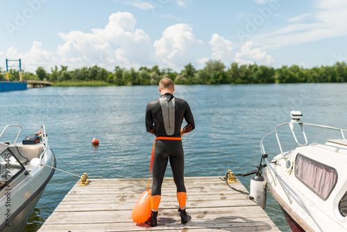 A swimmer in a wetsuit with a buoy prepares to swim © Ivan