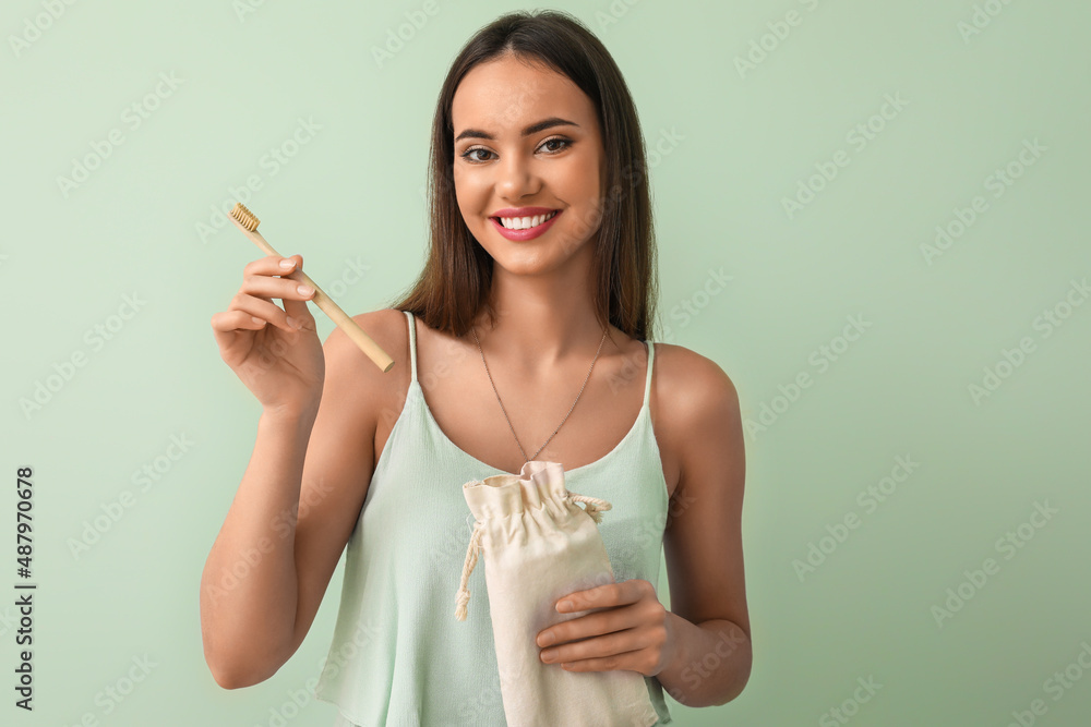 Young woman with bamboo tooth brush and eco bag on green background Young woman with bamboo tooth brush and eco bag on green background