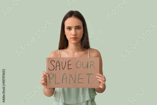 Young woman holding cardboard paper with text SAVE OUR PLANET on green background