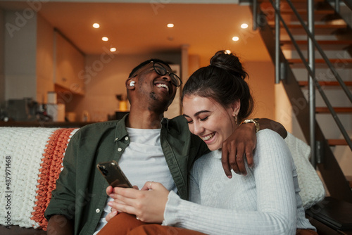 Photos Biracial couple laughing while texting on cellular device