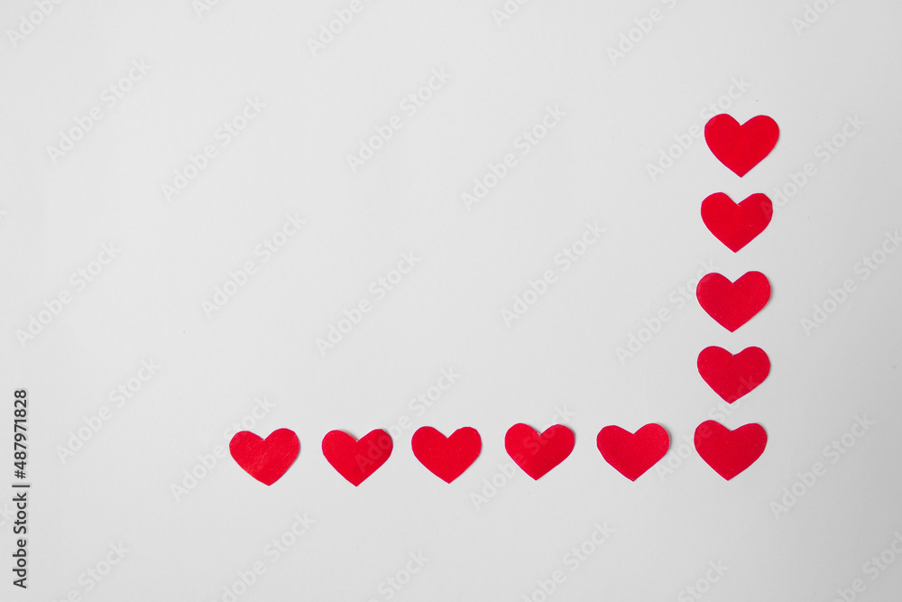 Frame of many red paper hearts in the lower right corner. White background. Minimalism. Valentine's Day concept. Frame of many red paper hearts in the lower right corner. White background. Minimalism. Valentine's Day concept.