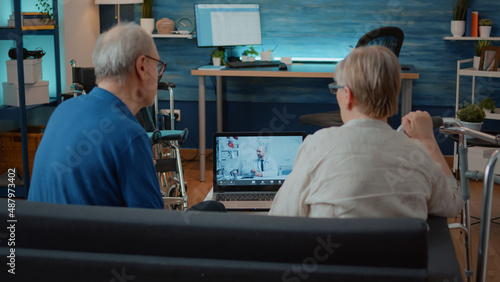 Elder couple using remote teleconference to talk to medic on laptop, asking about treatment. Senior people discussing about health care with doctor on online conference call at home.