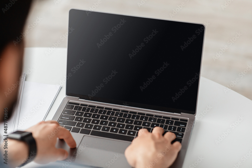 Lifestyle and gadgets concept. Unrecognizable adult man using laptop with blank black screen for mockup template Lifestyle and gadgets concept. Unrecognizable adult man using laptop with blank black screen for mockup template