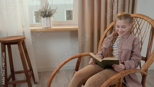 girl reading a book sitting in a rocking chair photo
