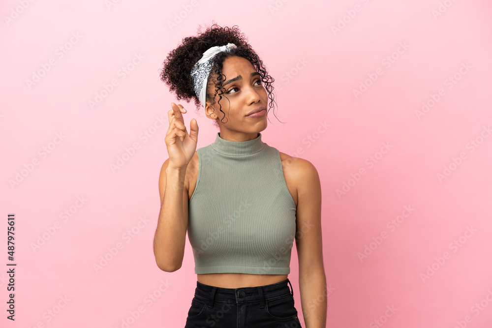 Young latin woman isolated on pink background with fingers crossing and wishing the best Young latin woman isolated on pink background with fingers crossing and wishing the best