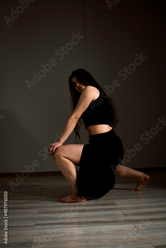 Slender flexible dance performer during a dance practice in modern studio