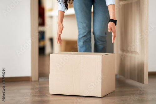 Unrecognizable woman picking cardboard box up from the floor © Prostock-studio