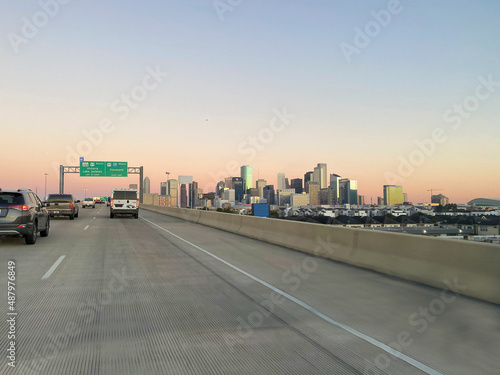 Houston downtown skyline at sunrise with pastel orange to yellow clouds and a blue sky shot from freeway in morning traffic. Clear crisp morning. © Liana Lopez