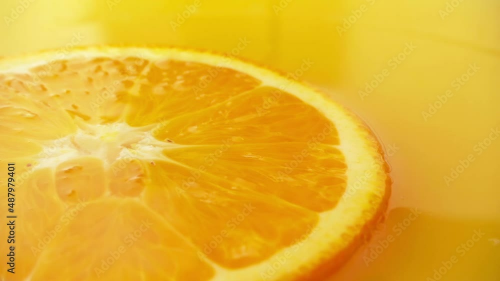 A slice of orange floats in juice, a falling drop. Slow motion. A slice of orange floats in juice, a falling drop. Slow motion.
